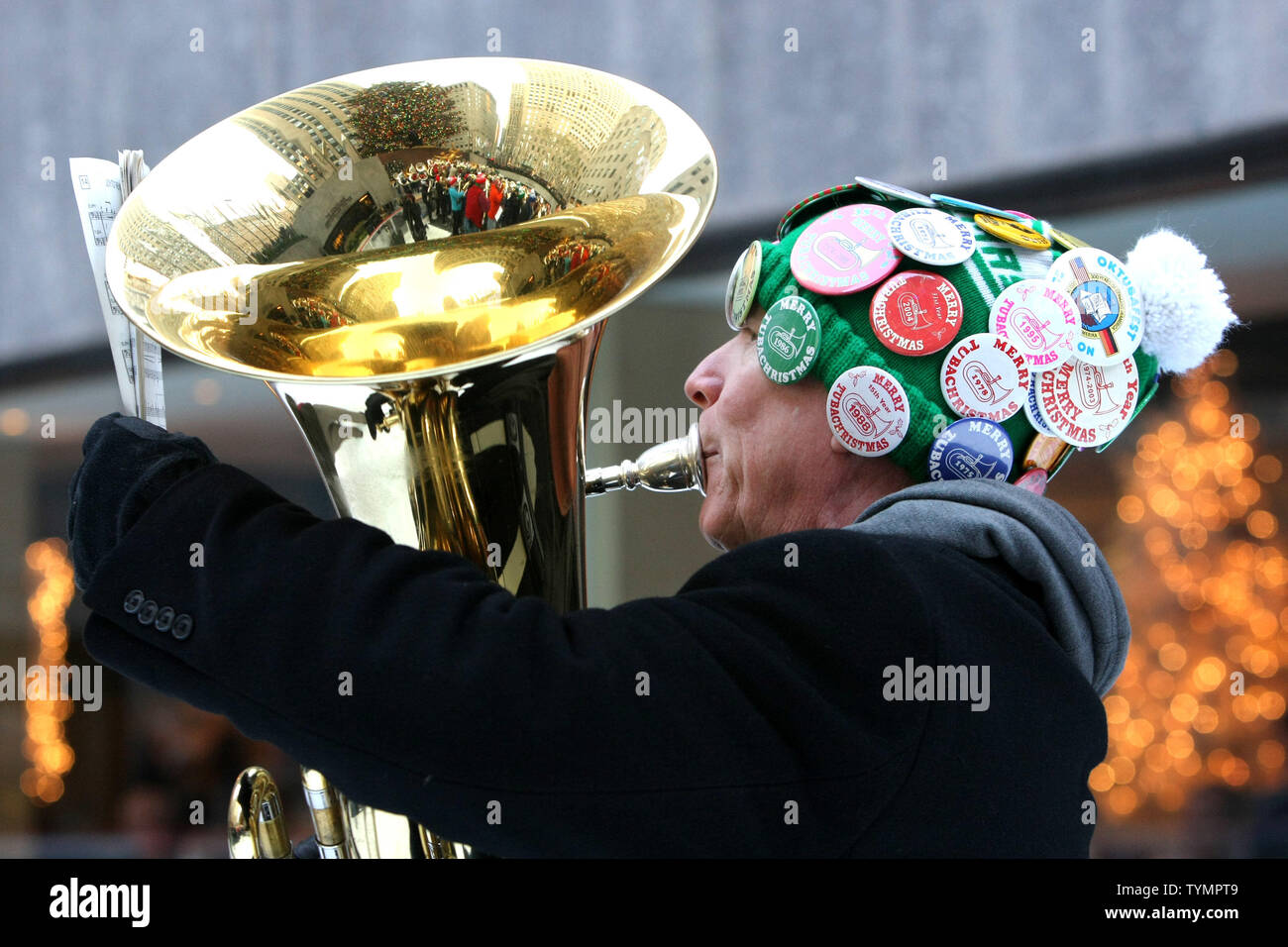 The reflection of surrounding buildings are seen in a tuba as hundreds