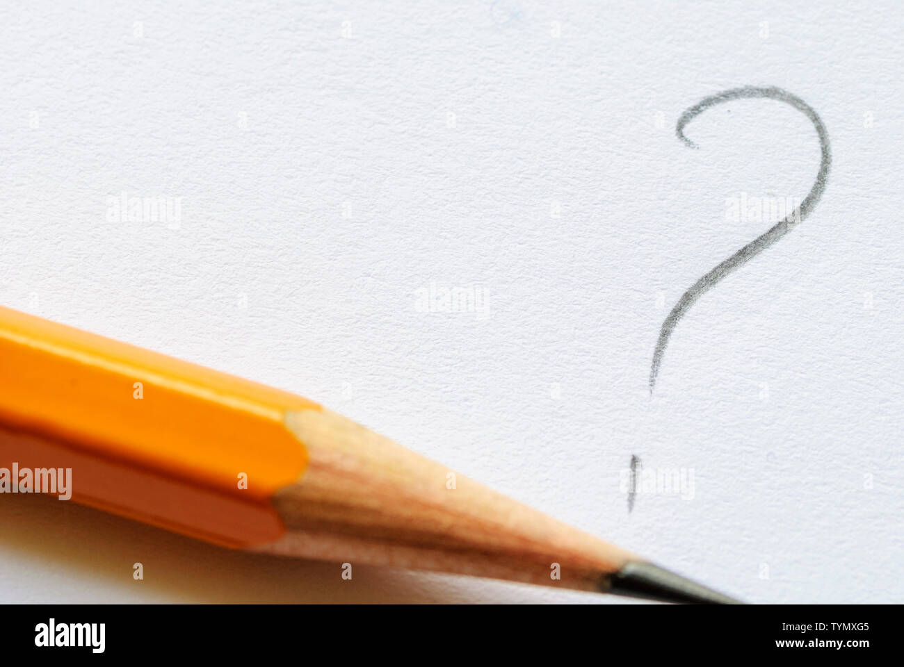 Sharp pencil lying next to question mark on white paper with copy space