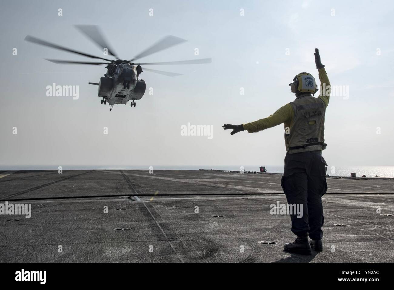 GULF (Nov. 17, 2016) Petty Officer 3rd Class Joshua Broadbent signals to an MH-53E Sea Dragon helicopter assigned to the Blackhawks of Helicopter Mine Countermeasures Squadron (HM) 15 on the flight deck of the aircraft carrier USS Dwight D. Eisenhower (CVN 69). Broadbent serves aboard the ship as an aviation boatswain's mate (handling). Eisenhower and its carrier strike group are deployed in support of Operation Inherent Resolve, maritime security operations and theater security cooperation efforts in the U.S. 5th Fleet area of operations. Stock Photo