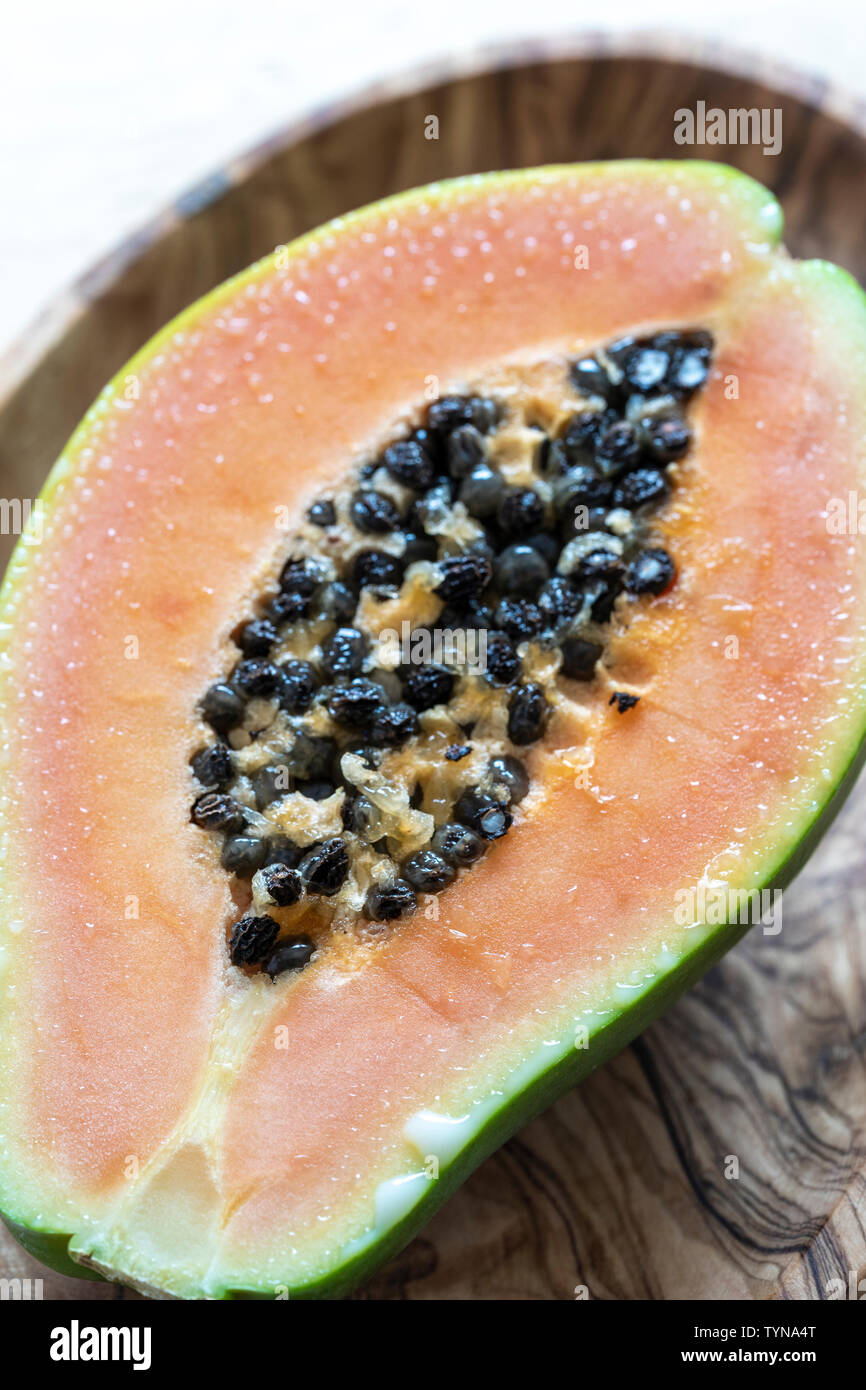 Papaya fruit cut in half showing seeds close up with foreground focus