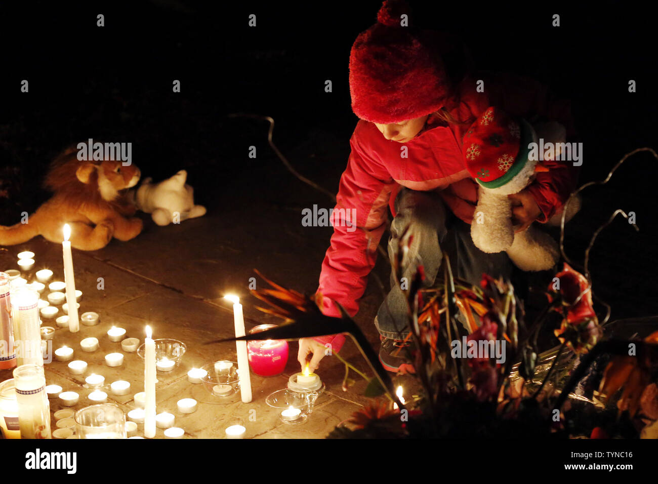 A child lights a candle at a memorial filled with flowers, stuffed toys and candles outside of Saint Rose of Lima Church near Sandy Hook Elementary School in Newtown, Connecticut following a A child lights a candle at a memorial filled with flowers, stuffed toys and candles outside of Saint Rose of Lima Church near Sandy Hook Elementary School in Newtown, Connecticut following a