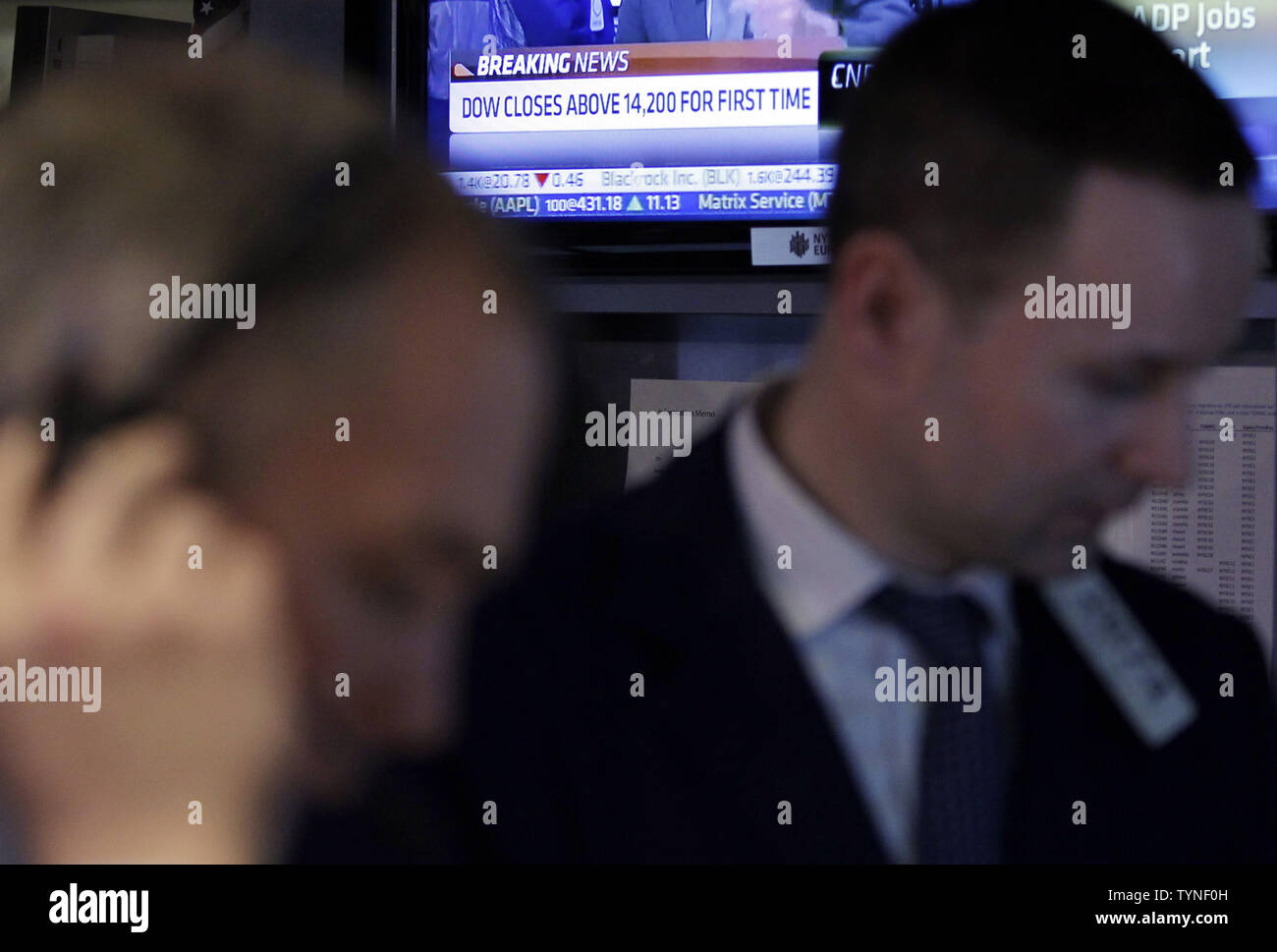 Televisions at the NYSE show the Dow Jones Industrial Average above