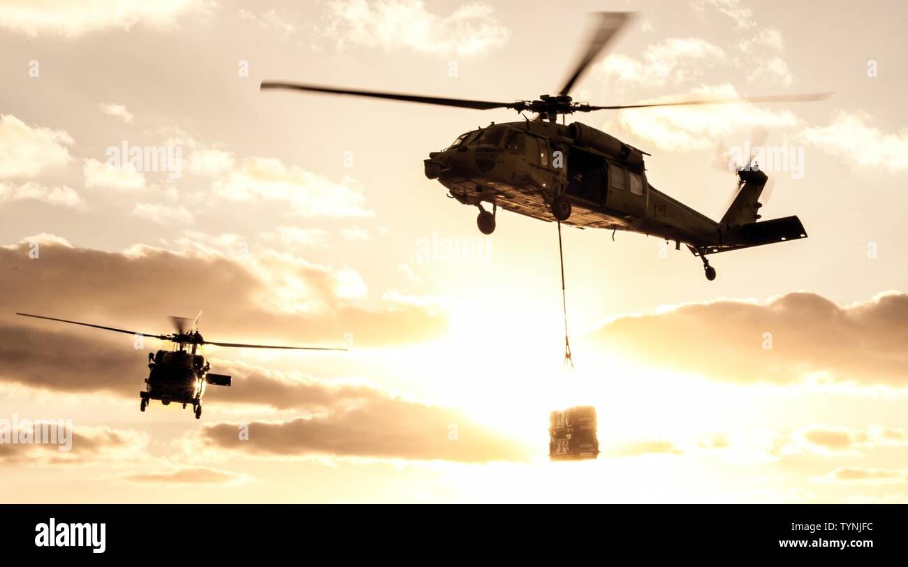 PHILIPPINE SEA (Nov. 18, 2016) MH-60S Sea Hawks from the “Island Knights” of Helicopter Sea Combat Squadron (HSC) 25 transport ordnance from the flight deck of the Navy’s only forward-deployed aircraft carrier, USS Ronald Reagan (CVN 76), to USNS Charles Drew (T-AKE 10) during an ammunition offload. Ronald Reagan, the Carrier Strike Group Five (CSG 5) flagship, is on patrol supporting security and stability in the Indo-Asia-Pacific region. Stock Photo