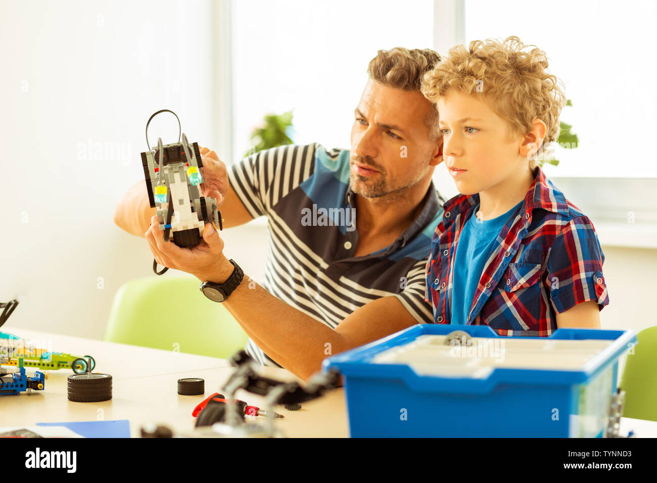 Robot construction. Serious excited boy looking at the robot ...