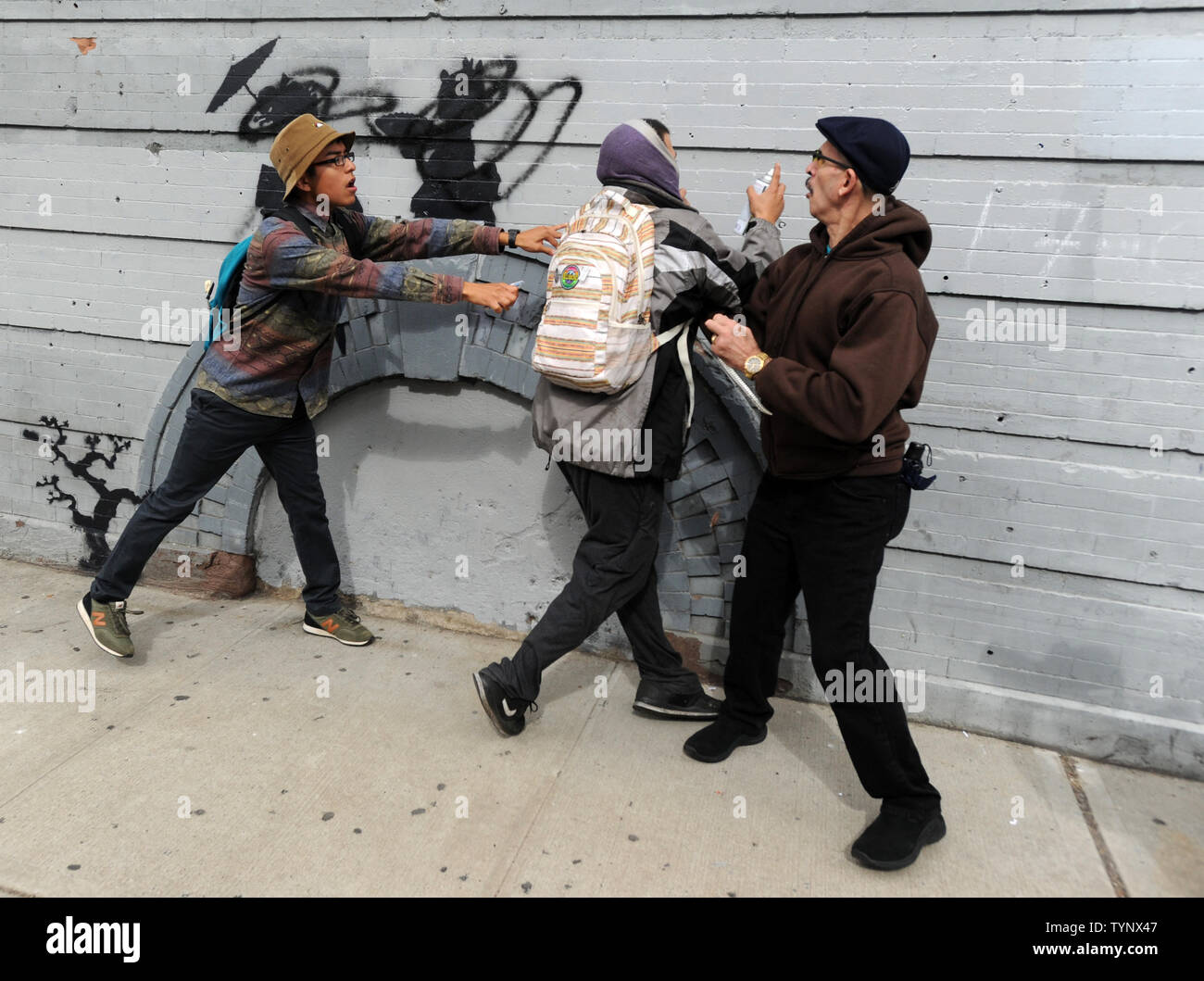 Bystanders try to stop man from spray painting over an art piece created by British street artist Banksy in Williamsburg in New York City on October 17, 2013. Banksy is a pseudonymous England-based graffiti artist, political activist, film director, and painter. His satirical street art and subversive epigrams combine dark humor with graffiti done in a distinctive stenciling technique.    UPI/Dennis Van Tine Stock Photo
