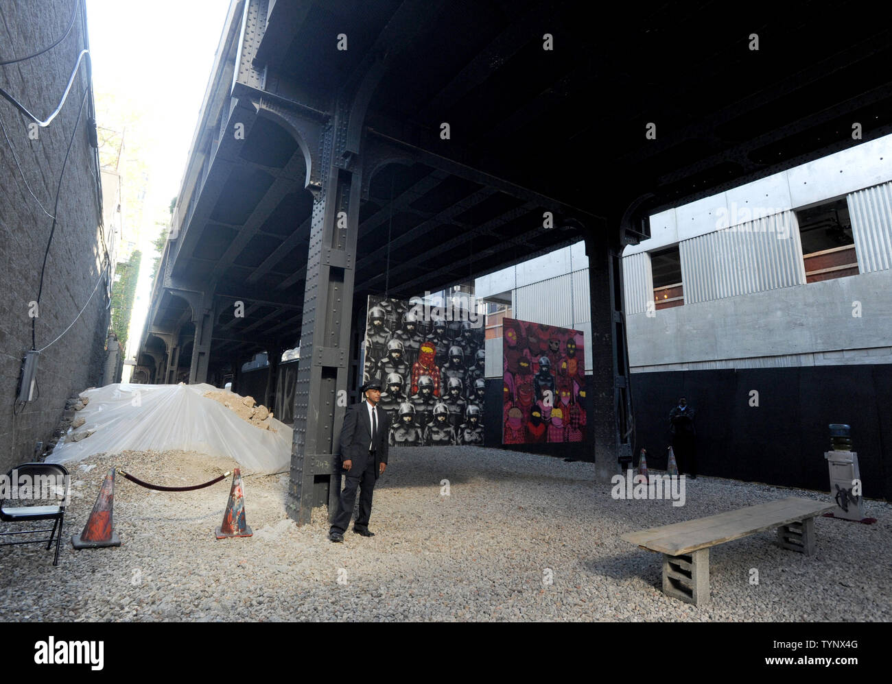 A security guard protects a temporary exhibition space with art pieces created by  British street artist Banksy on the west side of Manhattan in New York City on October 18, 2013. Banksy is a pseudonymous England-based graffiti artist, political activist, film director, and painter. His satirical street art and subversive epigrams combine dark humor with graffiti done in a distinctive stenciling technique.    UPI/Dennis Van Tine Stock Photo