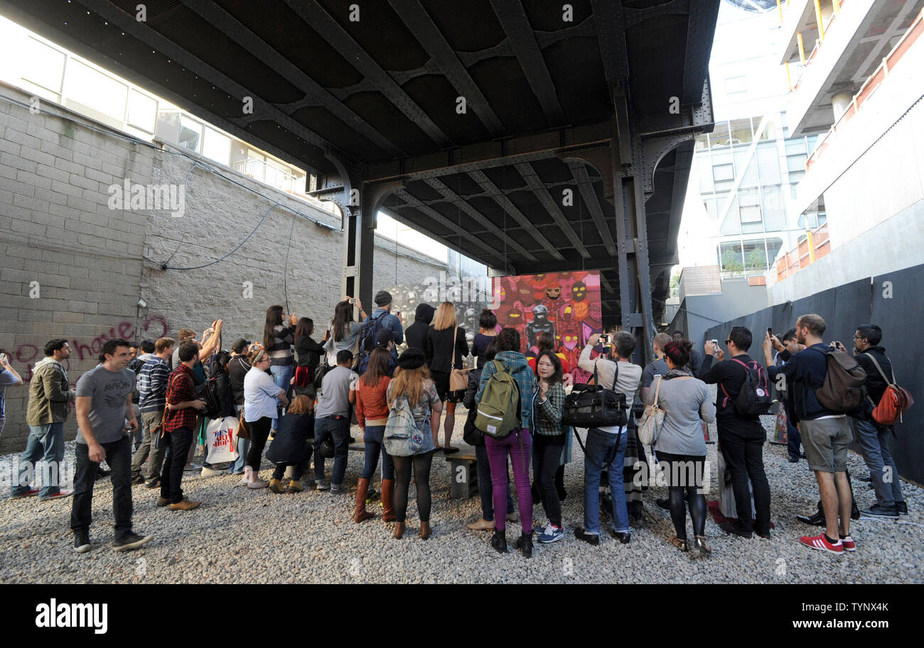 People gather to view a temporary exhibition space with art pieces created by British street artist Banksy on the west side of Manhattan in New York City on October 18, 2013. Banksy is a pseudonymous England-based graffiti artist, political activist, film director, and painter. His satirical street art and subversive epigrams combine dark humor with graffiti done in a distinctive stenciling technique.    UPI/Dennis Van Tine Stock Photo