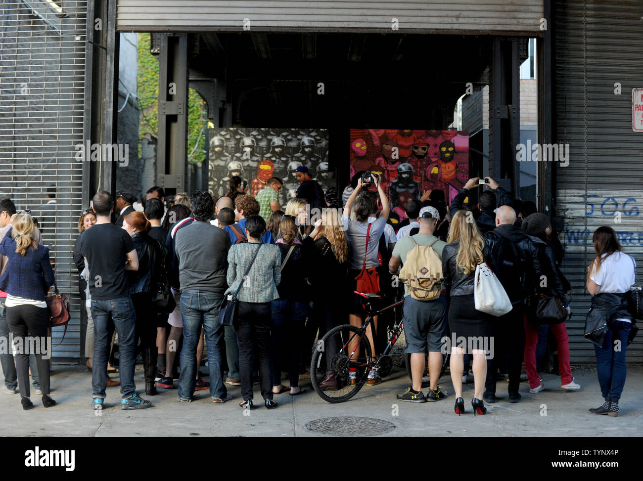 People gather to view a temporary exhibition space with art pieces created by British street artist Banksy on the west side of Manhattan in New York City on October 18, 2013. Banksy is a pseudonymous England-based graffiti artist, political activist, film director, and painter. His satirical street art and subversive epigrams combine dark humor with graffiti done in a distinctive stenciling technique.    UPI/Dennis Van Tine Stock Photo