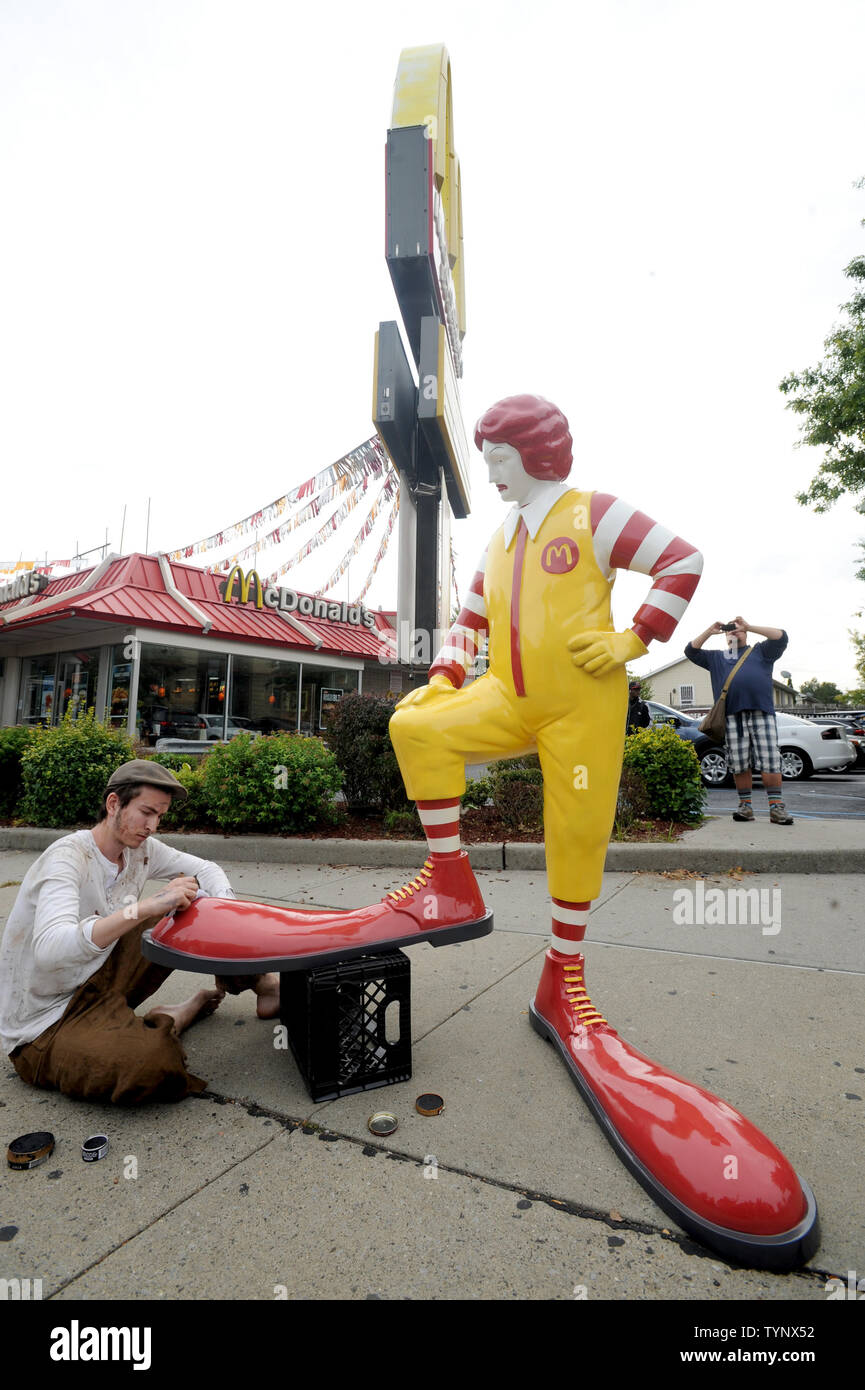 A fiberglass replica of Ronald McDonald having his shoes shined by a real live boy will visit the sidewalk outside a different McDonalds every lunchtime for the next week as a work of British street artist Banksy in New York City on October 16, 2013. Banksy is a pseudonymous England-based graffiti artist, political activist, film director, and painter. His satirical street art and subversive epigrams combine dark humor with graffiti done in a distinctive stenciling technique.    UPI/Dennis Van Tine Stock Photo