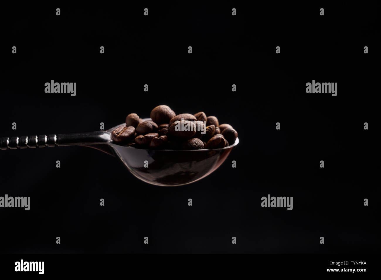 A spoonful of coffee beans in a black background Stock Photo Alamy