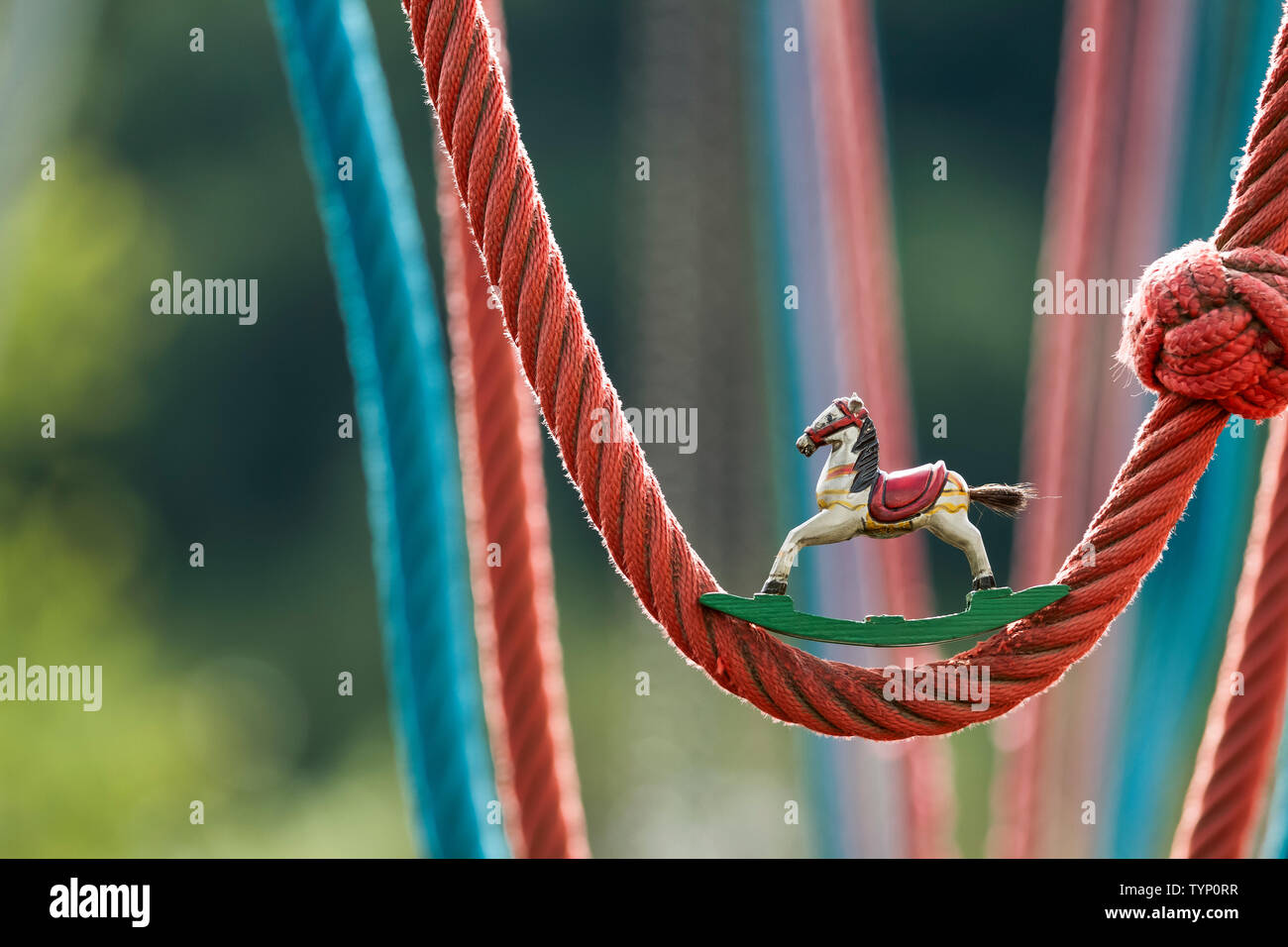 wooden antique rocking horse at a colorful playground with rope swings
