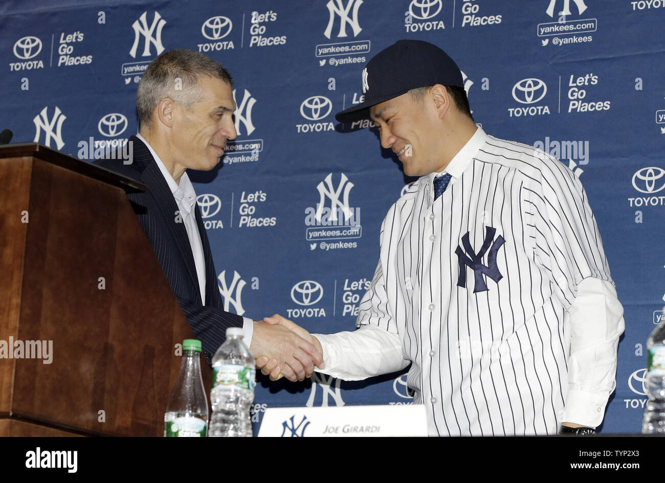 New York Yankees Manager Joe Girardi shakes hands with Masahiro Tanaka who  is wearing his new Yankee jersey and cap at a press conference at Yankee  Stadium in New York City on