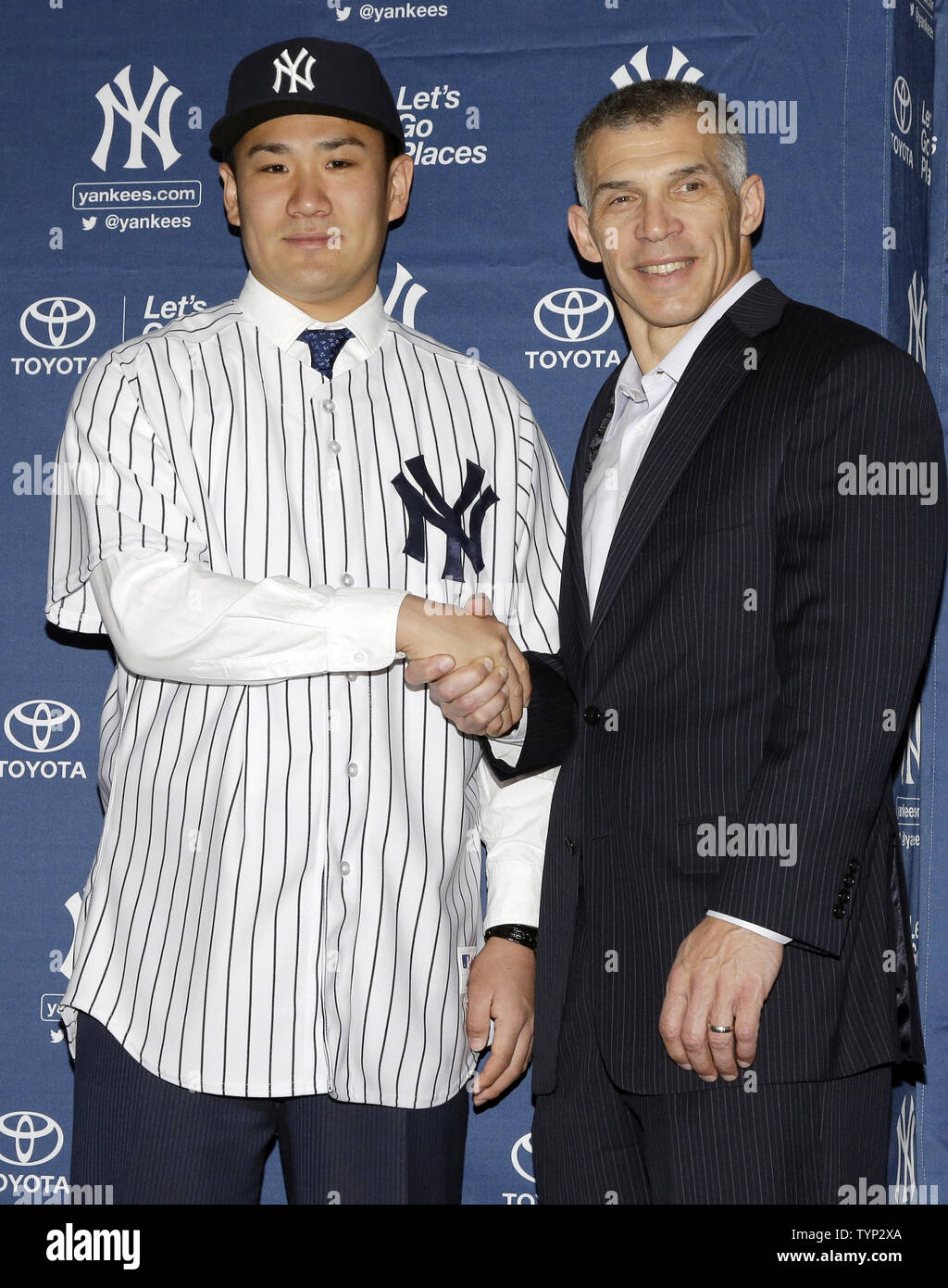 New York Yankees Manager Joe Girardi shakes hands with Masahiro Tanaka who  is wearing his new Yankees jersey and cap at a press conference at Yankee  Stadium in New York City on