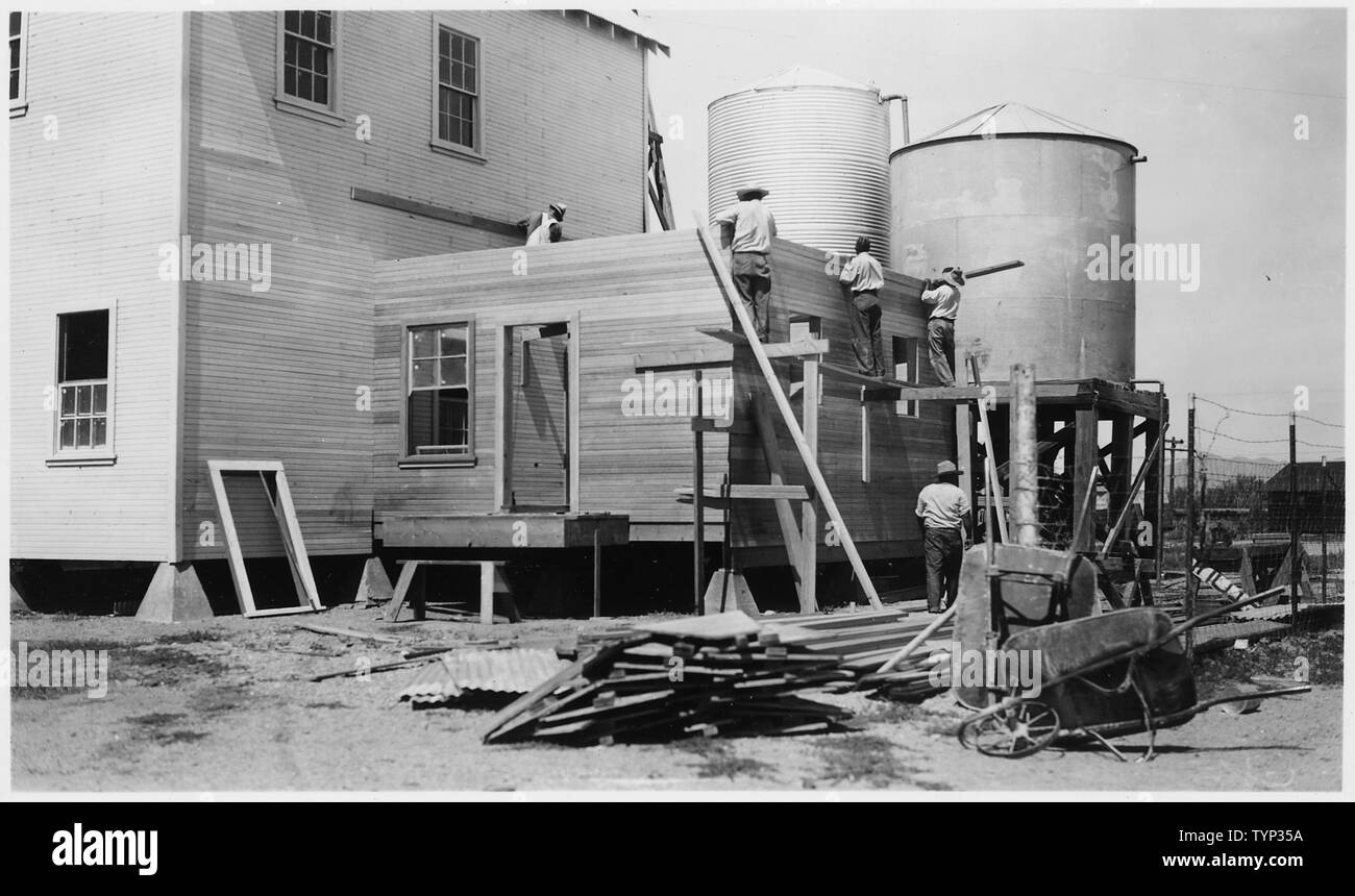 [View showing backside of building adjacent to two water towers and men
