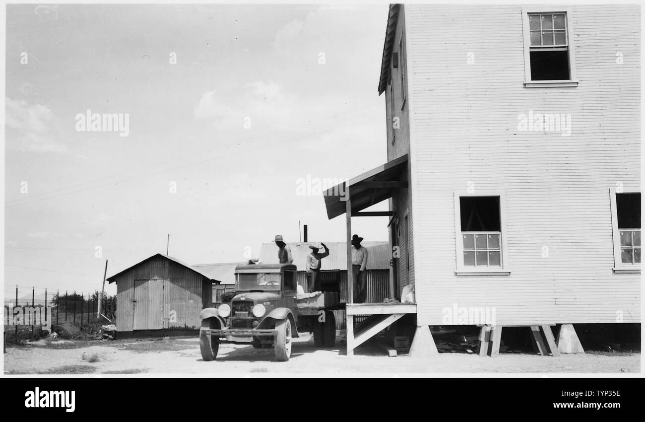 [View showing side of building with one man standing on porch and three