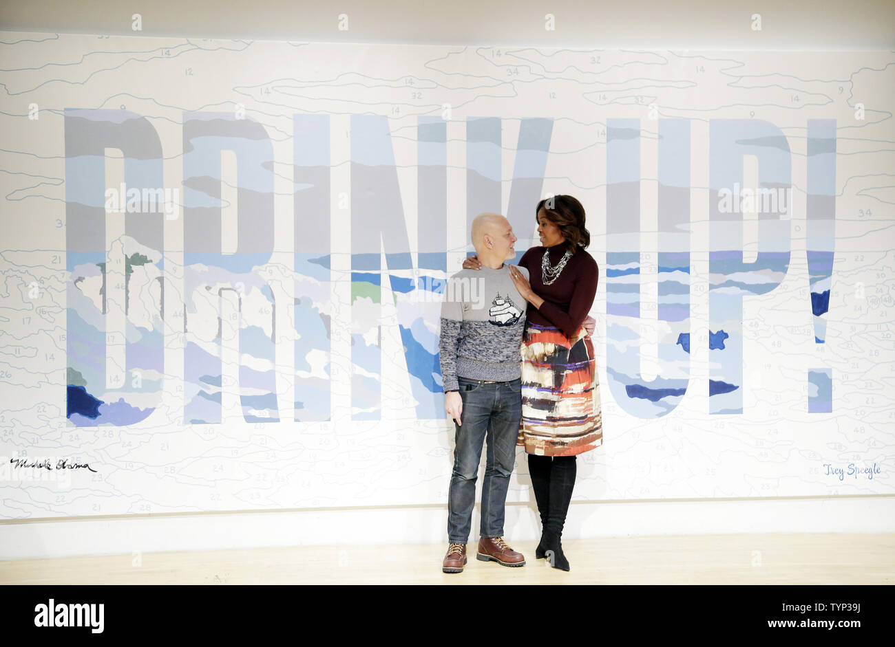 First Lady Michelle Obama stands with artist Trey Speegle when she visits the New Museum's 'Taking Back the Streets' exhibit, sponsored by Let Water Be Water LLC's youth bottled water brand WAT-AAH! to support the Partnership for a Healthier America's 'Drink Up' initiative in New York City on February 20, 2014.      UPI/John Angelillo Stock Photo