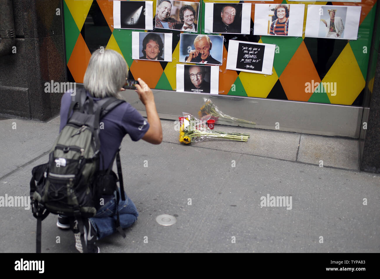 A man stops to take a photo of a tribute and memorial to the late Robin Williams at the entrance to Carolines on Broadway comedy club in New York City on August 12, 2014. Robin Williams committed suicide by hanging himself with a belt, the coroner said Tuesday in a press conference detailing the preliminary findings surrounding the actor and comedian's death.          UPI/John Angelillo Stock Photo