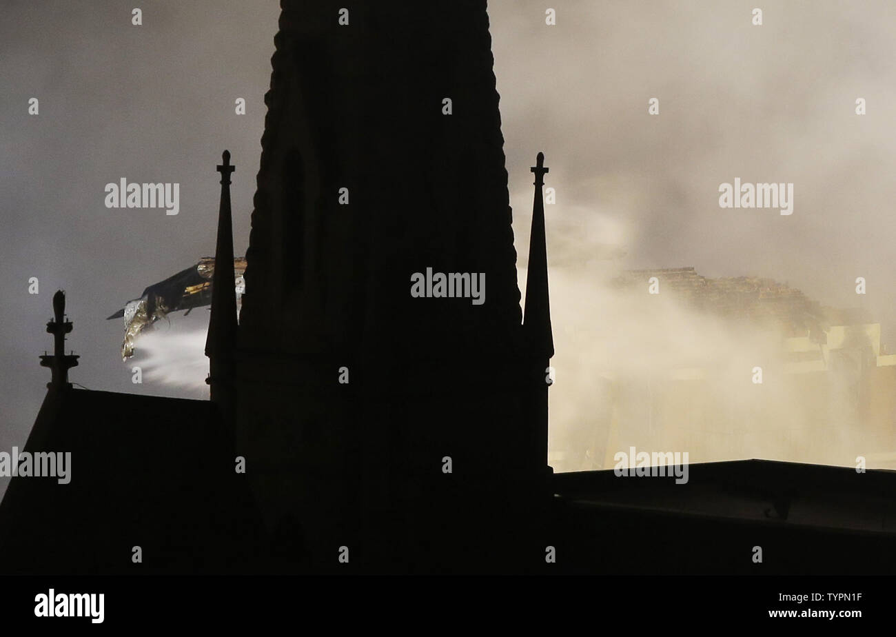 The Steeple of Middle Collegiate Church is in the shadows as FDNY firefighters work into the night fighting a fire with water after a building exploded in New York City on March 26, 2015. The powerful explosion in the East Village caused one building to collapse and ignited a large fire that engulfed a neighboring building on Thursday afternoon, leaving at least a dozen people injured and at least three of them critically.    Photo by John Angelillo/UPI Stock Photo