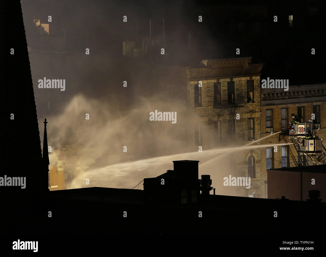 The Steeple of Middle Collegiate Church is in the shadows as FDNY firefighters work into the night fighting a fire after a building exploded in New York City on March 26, 2015. The powerful explosion in the East Village caused one building to collapse and ignited a large fire that engulfed a neighboring building on Thursday afternoon, leaving at least a dozen people injured and at least three of them critically.    Photo by John Angelillo/UPI Stock Photo