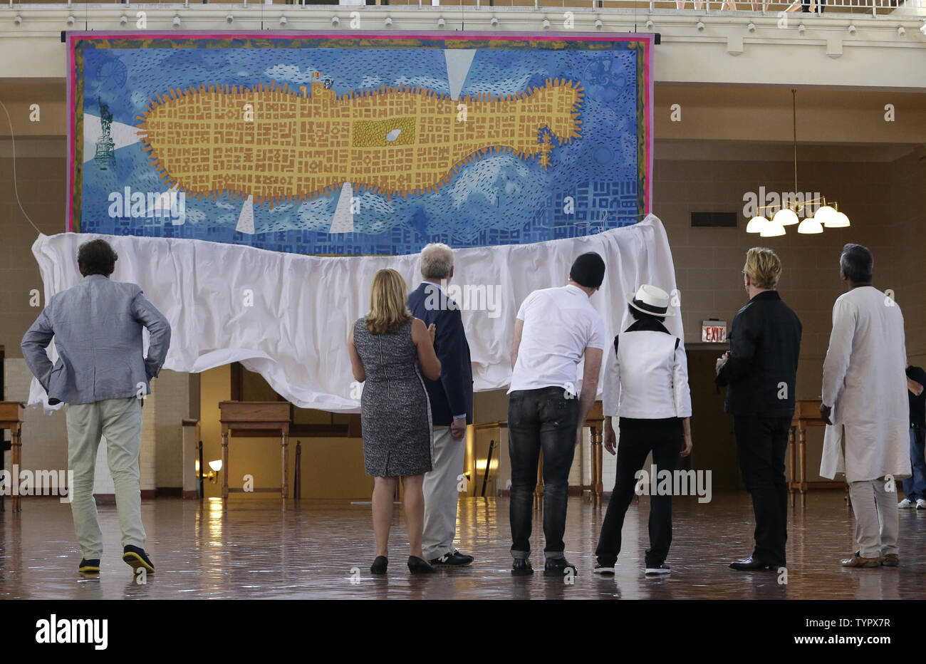 Yoko Ono, Bono and The Edge of U2 watch the unveiling of a giant 24' x 10' tapestry honoring John Lennon in the presence Amnesty International Secretary General Salil Shetty at the Ellis Island National Museum of Immigration in New York City on July 29, 2015. The tapestry was commissioned by Art for Amnesty founder Bill Shipsey as a thank you to Ono for giving Amnesty International the rights to record cover versions of Lennon's post-Beatles songs in 2004, allowing Amnesty to raise over $5 million in royalties since. Bono, The Edge and music business impresario Jimmy Iovine have donated the ta Stock Photo