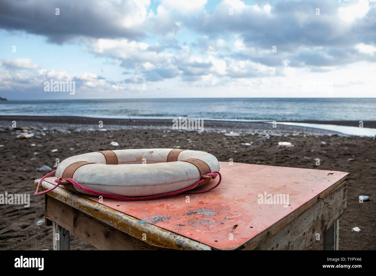 red and white life belt lying on a rusty table at an Italian beach with black  volcanic sand Stock Photo