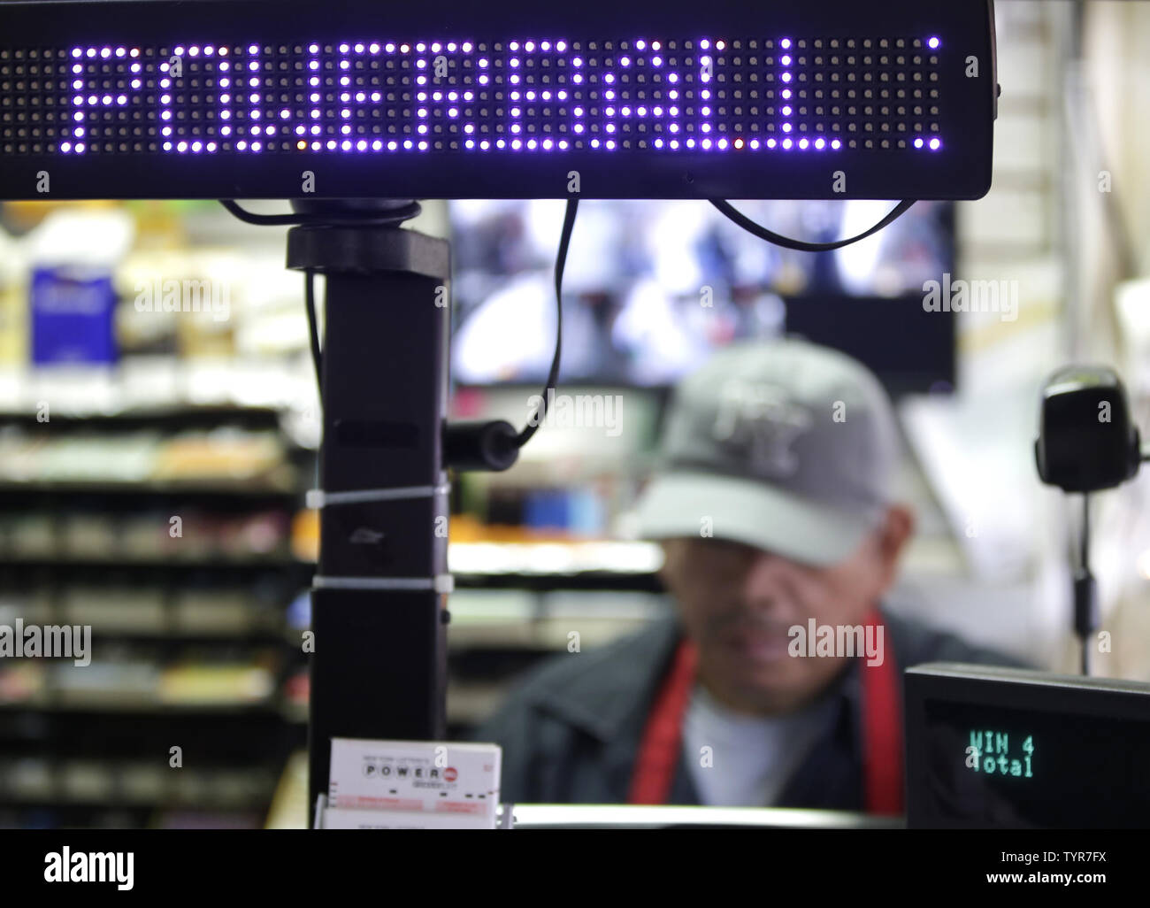 A digital powerball lottery display is above the check out counter at a