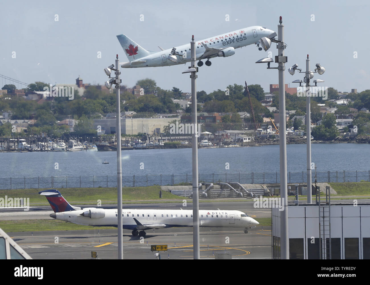 An Air Canada plane takes off over a Delta Airlines plane that remains on the runway at LaGuardia Airport in New York City on August 8, 2016 in New York City. Delta began to resume flights but still expect massive cancelations and delays after after a computer glitch shut down the airline completely this morning.    Photo by John Angelillo/UPI Stock Photo