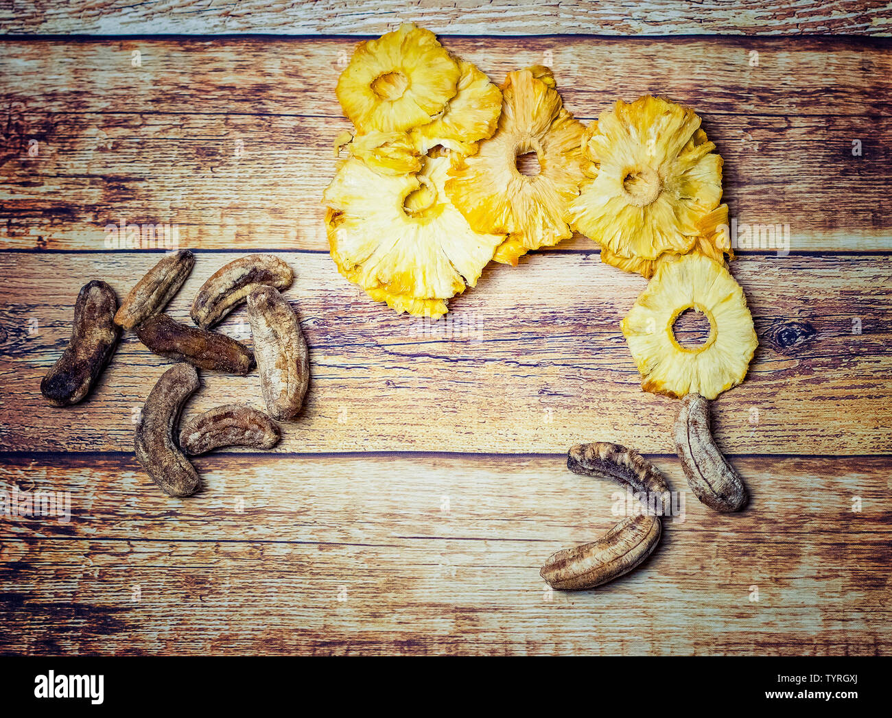 Dried pineapples and dried small bananas on a wooden background