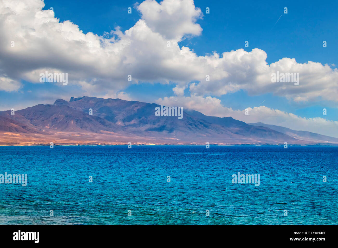 View of the hill on the island Fuerteventura near Morro Jable, Canary islands, Spain. There is clear blue water and beautiful sky. Stock Photo