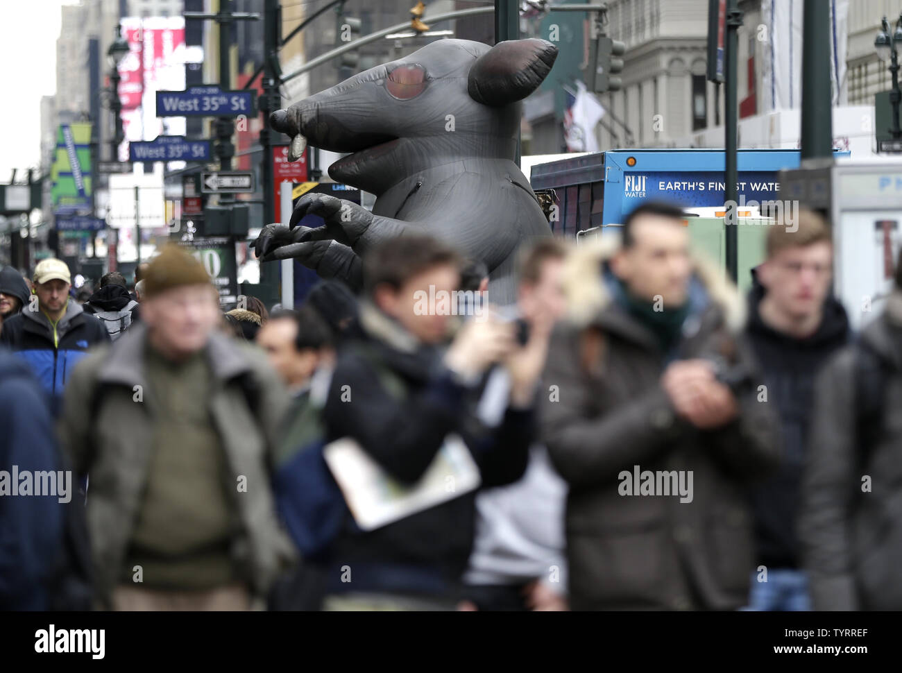 Pedestrians walk past a giant inflatable rat on the sidewalks along ...
