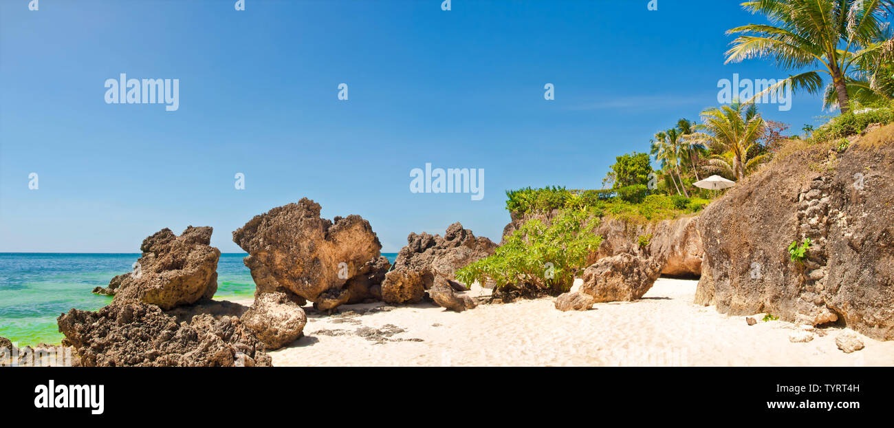 panoramic view of private white sanded rocky tropical beach with umbrella on sunny day, Boracay island, the Philippines Stock Photo