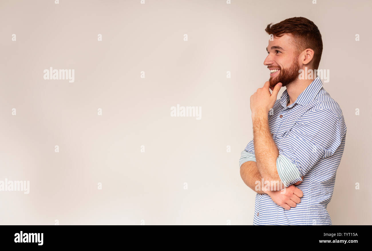 Young smiling man thinking and looking away on free space Stock Photo