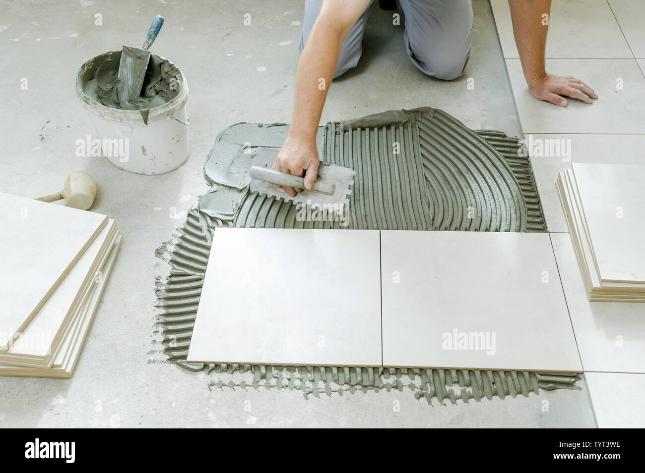 A tiler is putting tiles adhesive to the wall with the notched trowel