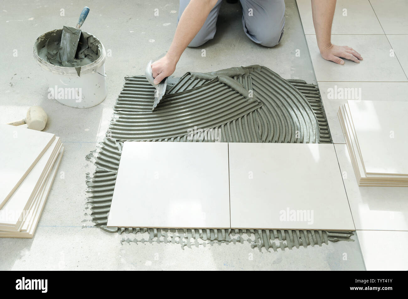 A tiler is putting tiles adhesive to the wall with the notched trowel
