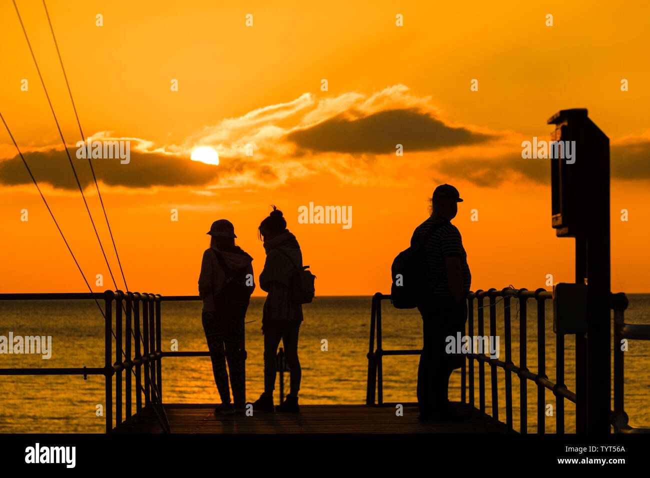 Aberystwyth Wales UK, Wednesday   26 June 2019  UK Weather: People  on the pier watching the glorious sunset in Aberystwyth on the Cardigan Bay coast, west Wales, as the country heads into a spell of fine weather and the hottest days of the summer so far,  with temperatures expected to reach the high 20’s centigrade   photo credit: Keith Morris/Alamy Live News Stock Photo