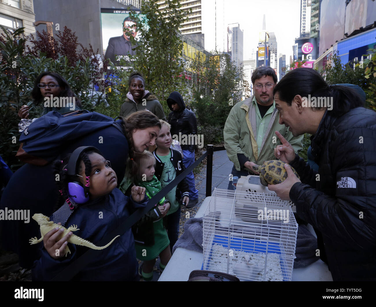 Isis Melina Leon (L) holds her plastic lizard as staff members of Your Connection To Nature show some rescued animals in a small "forest"  constructed for one day in Times Square on October 18, 2017 in New York City. The trees were placed as part of a promotion by LightStream, the on line lending division of SunTrust Bank, to plant up to 10,000 trees in October in the USA.    Photo by Ray Stubblebine/UPI Stock Photo