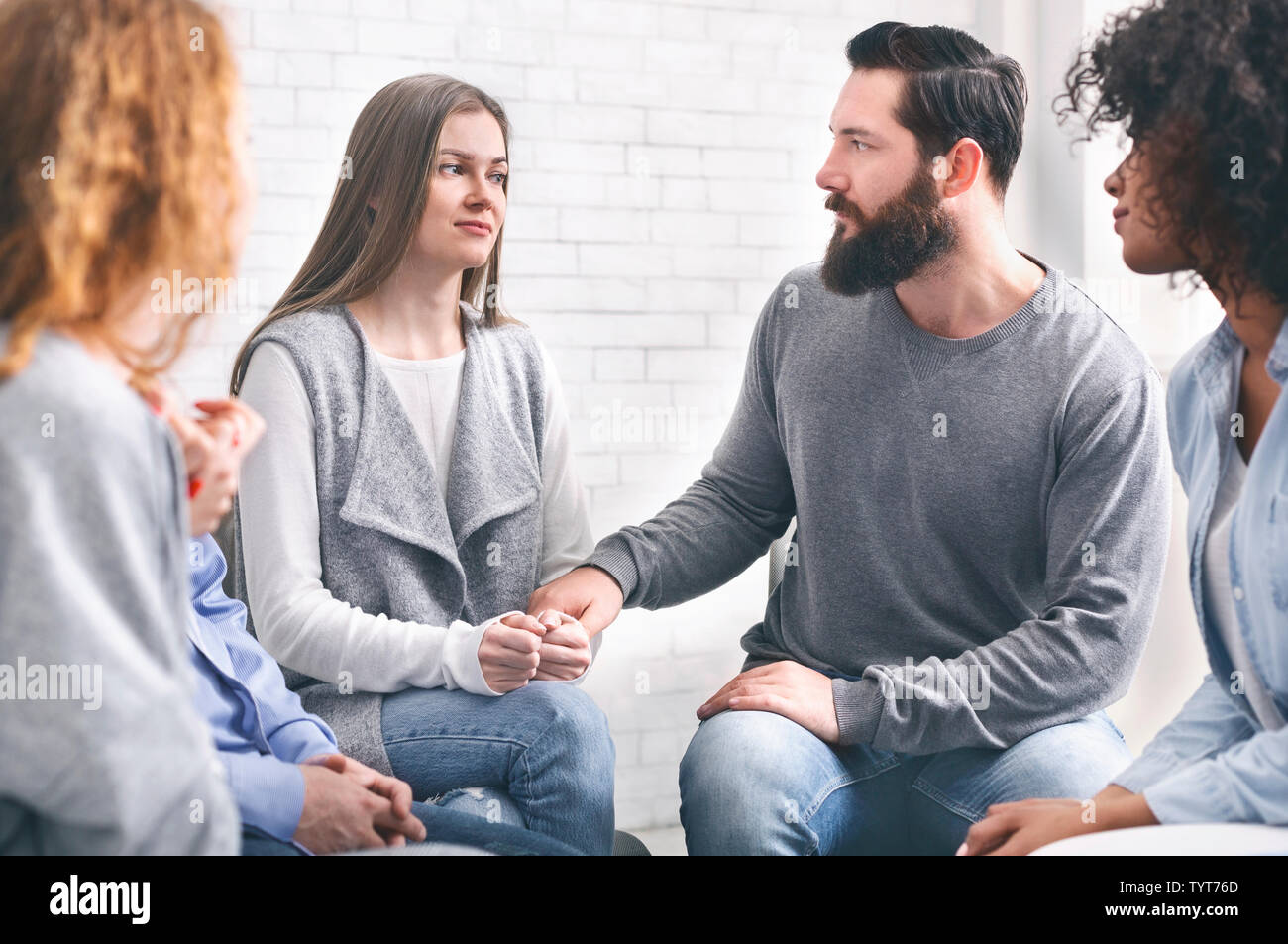 Depressed addicted woman sharing her problems at group meeting Stock Photo