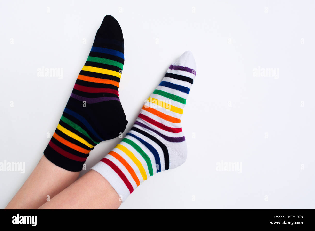 Woman legs wearing funny bright different striped colorful socks on white background with copy space. Flat lay. Top view. Black and white textile clot Stock Photo