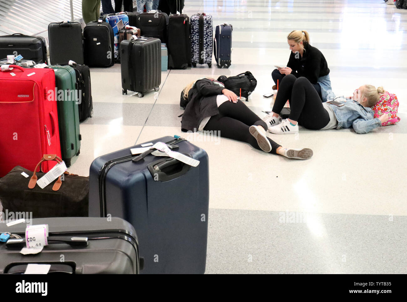 Travelers lie on the floor near baggage claim on a day where flights