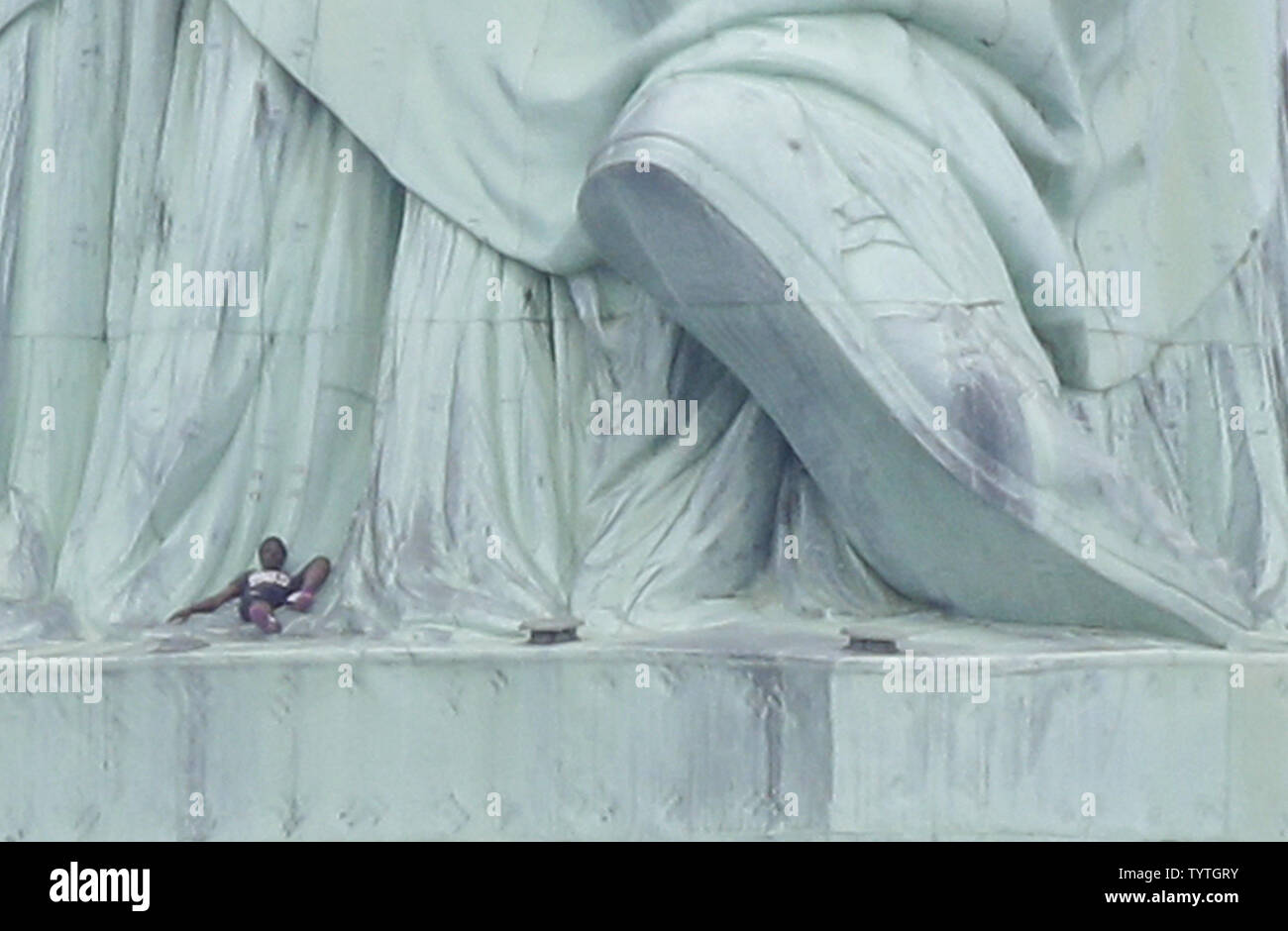 A woman lies down at the base of the back of the Statue of Liberty on ...