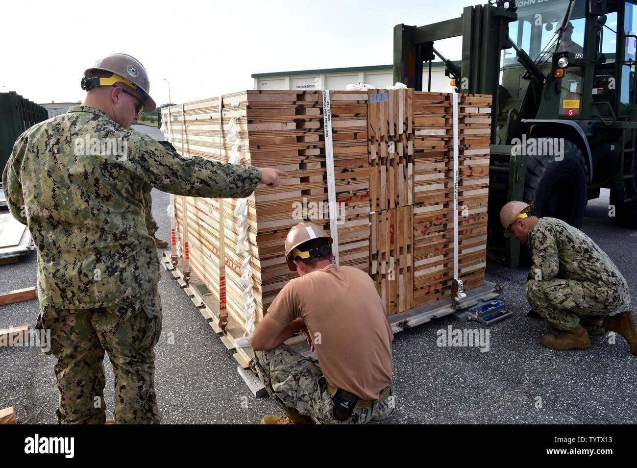 OKINAWA, Japan (Nov. 29, 2016) Petty Officer 2nd Class Bernard Barbuto, a Seabee assigned to Naval Mobile Construction Battalion (NMCB) 5, gives directions to a forklift operator while weighing a pallet on Camp Shields during an embark exercise. The exercise tests the commands ability to mobilize within 48 hours to react to different types of types of contingency operations around the world. NMCB 5 is the forward deployed Western Pacific NMCB ready to support Major Combat Operations, Humanitarian Assistance and Disaster Relief operations, and to provide general engineering and civil support to Stock Photo