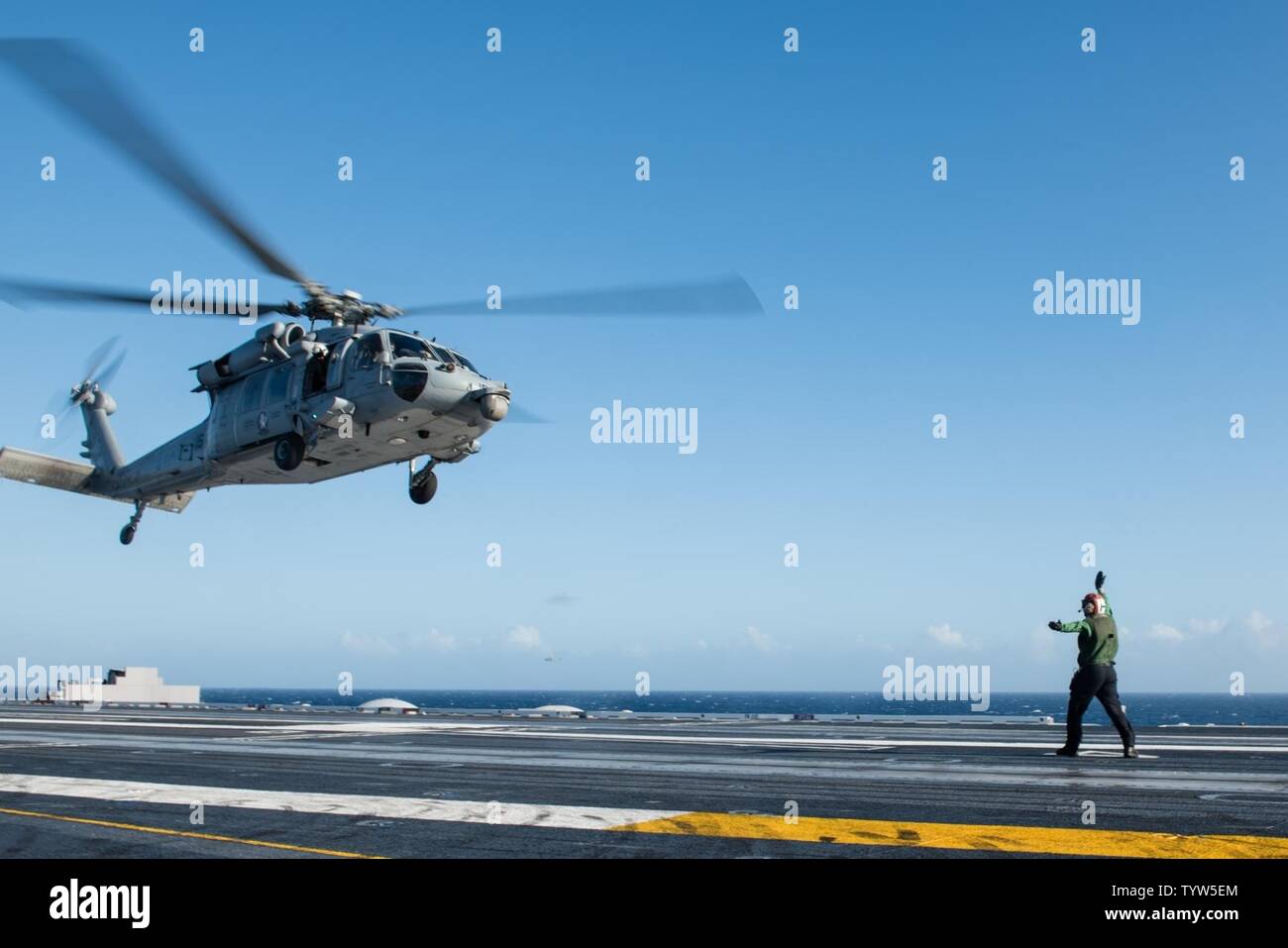 PACIFIC OCEAN (Nov. 30, 2016) Petty Officer 3rd Class Andrew Bate, from Boise, Idaho, directs an MH-60S Sea Hawk assigned to the Chargers of Helicopter Sea Combat Squadron (HSC) 14 to land on USS John C. Stennis' (CVN 74) flight deck. John C. Stennis is underway to conduct routine training and participate in National Pearl Harbor Remembrance Day events in Hawaii. Stock Photo