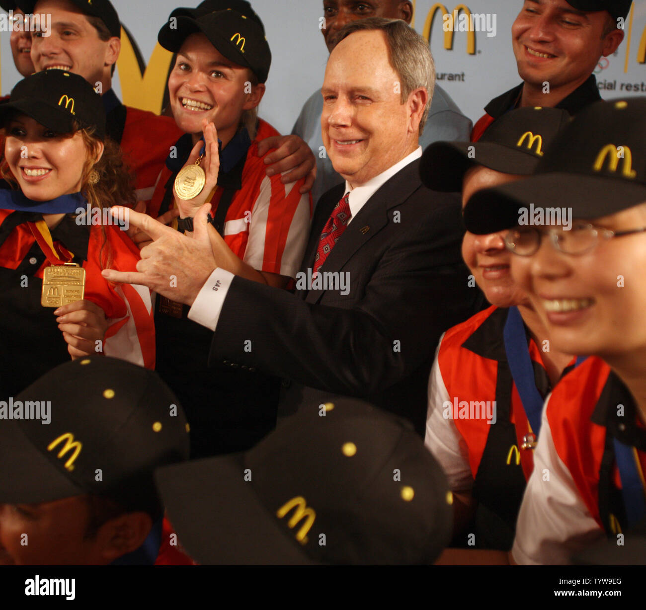 McDonald's Chief Executive Officer Jim Skinner poses with employees at a new McDonald's on the Olympic Green in Beijing on August 7, 2008. The hand sign is for 'I'm lovin' it'.  (UPI Photo/Terry Schmitt) Stock Photo