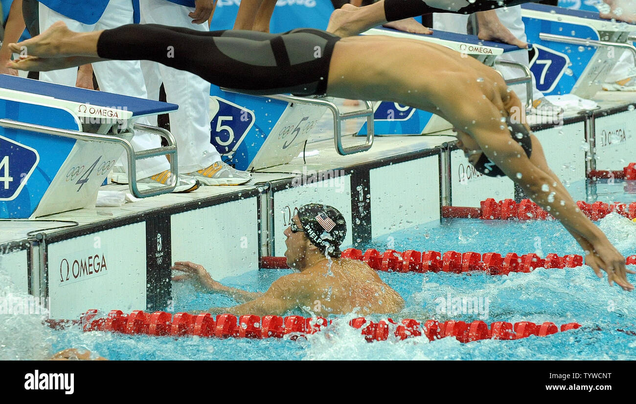 USA's Michael Phelps finishes the Butterfly part of the Men's 4x100M Medley, putting the US ahead and helping the US team set a world record and win gold, at the National Aquatic Center (Water Cube) during the 2008 Summer Olympics in Beijing, China, on August 17, 2008.  Phelps set the world record for medals in a single Olympics with 8, passing Mark Spitz. Diving in over Phelps is Japan's Hisayoshi Sato.    (UPI Photo/Roger L. Wollenberg) Stock Photo