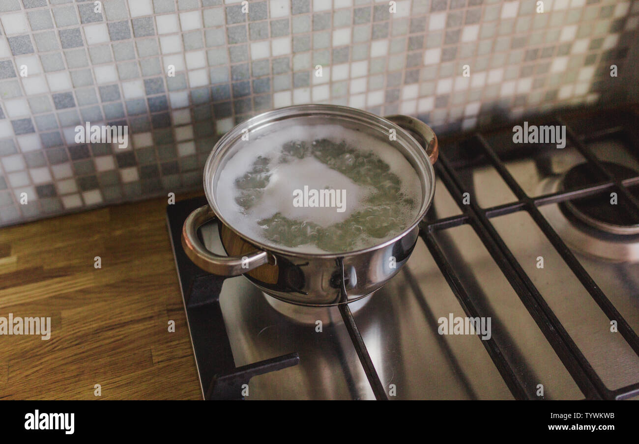 Saucepan on the stove in the kitchen on the background of a wooden tabletop Stock Photo