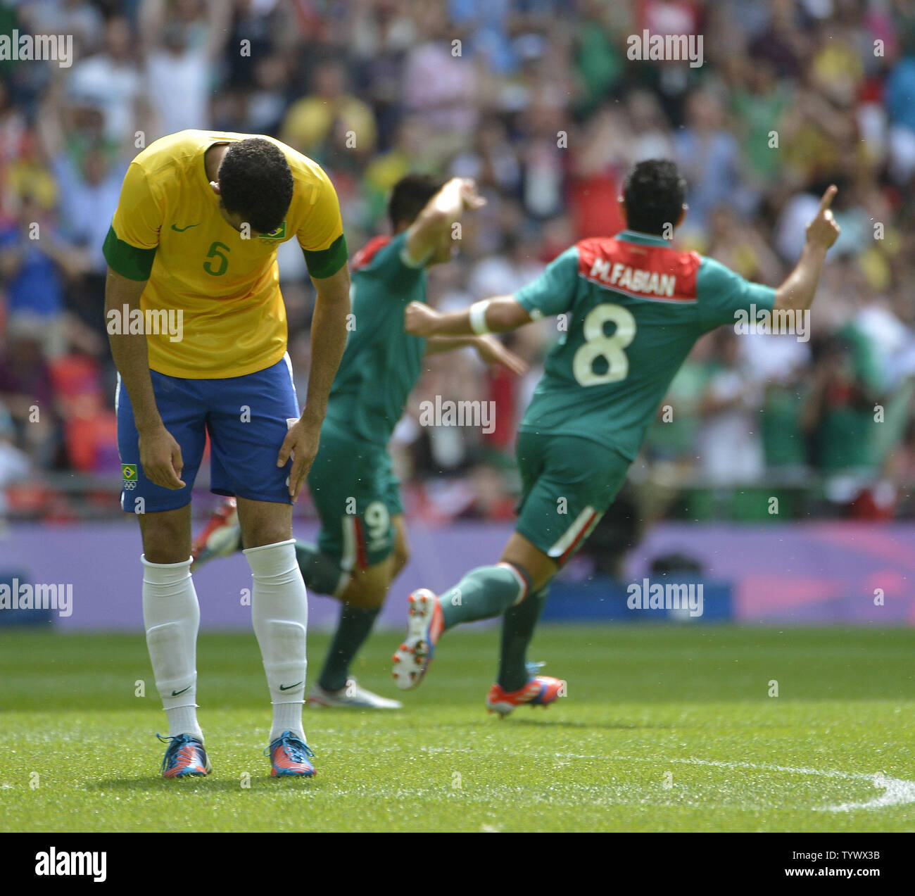 Sandro of Brazil (L) reacts as Oribe Peralta (C) and Marco Fabian of Mexico celebrate Peralta's goal during the first half of the Gold Medal Football Match at the London 2012 Summer Olympics on August 11, 2012 at Wembley Stadium, London.      UPI/Brian Kersey Stock Photo