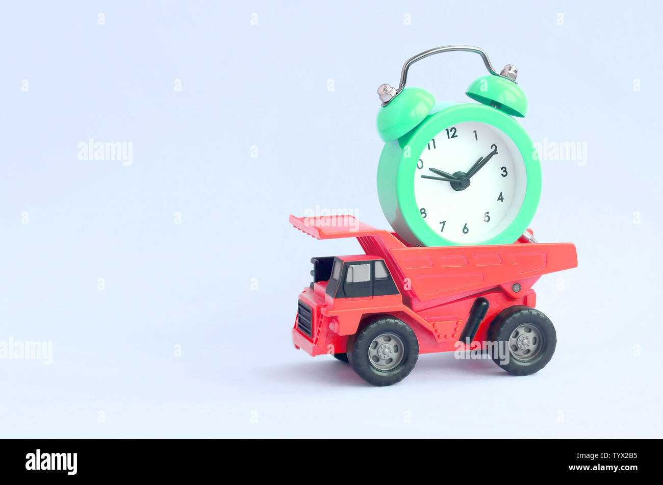 A dump truck loaded with an alarm clock on pastel blue background. The