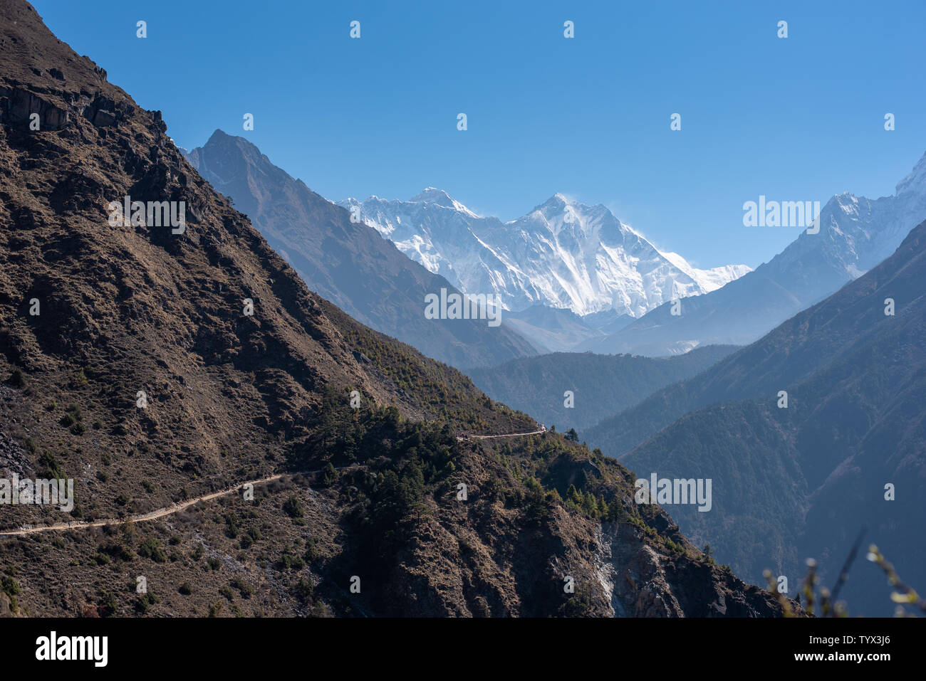 Rough scenery in Himalayas with Mount Everest and Lhotse, narrow hiking path alongside mountain slope Stock Photo