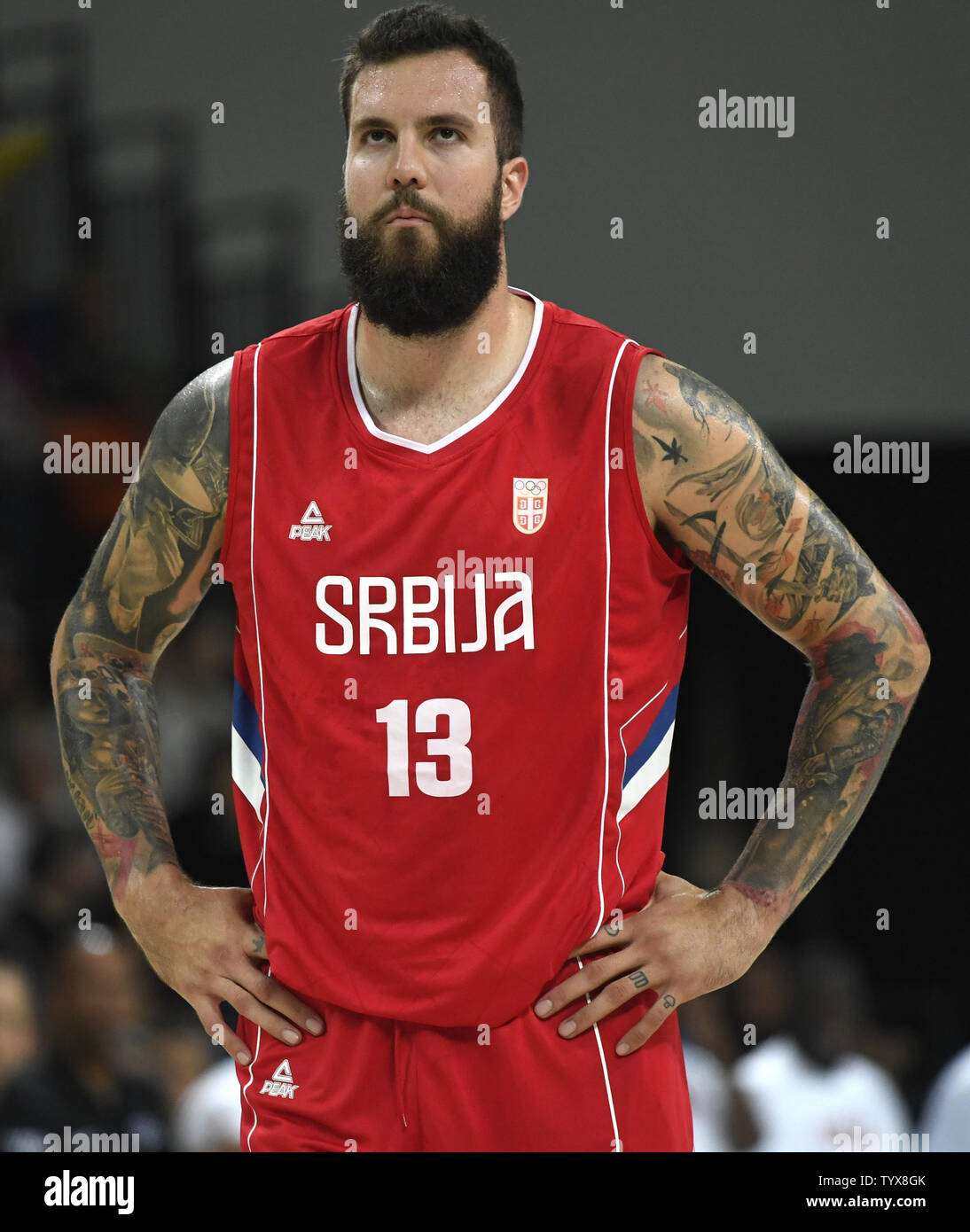 Serbian basketball center Miroslav Raduljica sports two "sleeves" of  tattoos on both arms showing dark figures, masks and swords as he awaits  the start of the the USA-Serbia basketball game at the