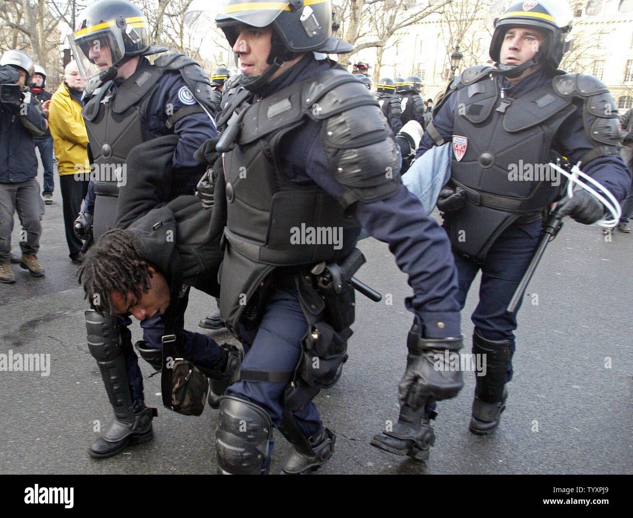 French anti-riot police carry away an arrested student protestors after a mass demonstration turned violent in Paris March 28, 2006. An estimated record three million people rallied countrywide to demand that the government repeapls the First Employment Contract (CPE). (UPI Photo/Eco Clement) Stock Photo